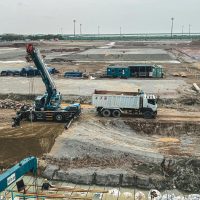 Aerial view of a construction site in West Java, Indonesia with crane and dump truck.