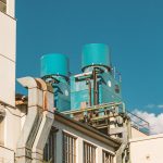 A close-up view of an industrial building with blue storage tanks against a bright blue sky.