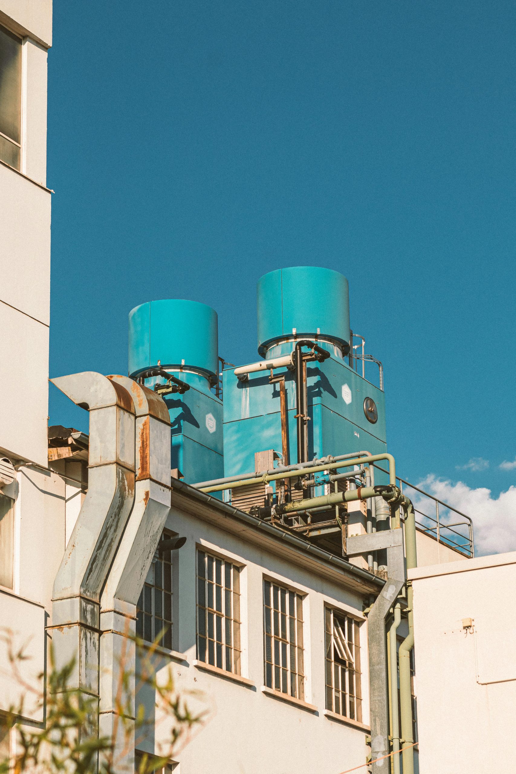 A close-up view of an industrial building with blue storage tanks against a bright blue sky.