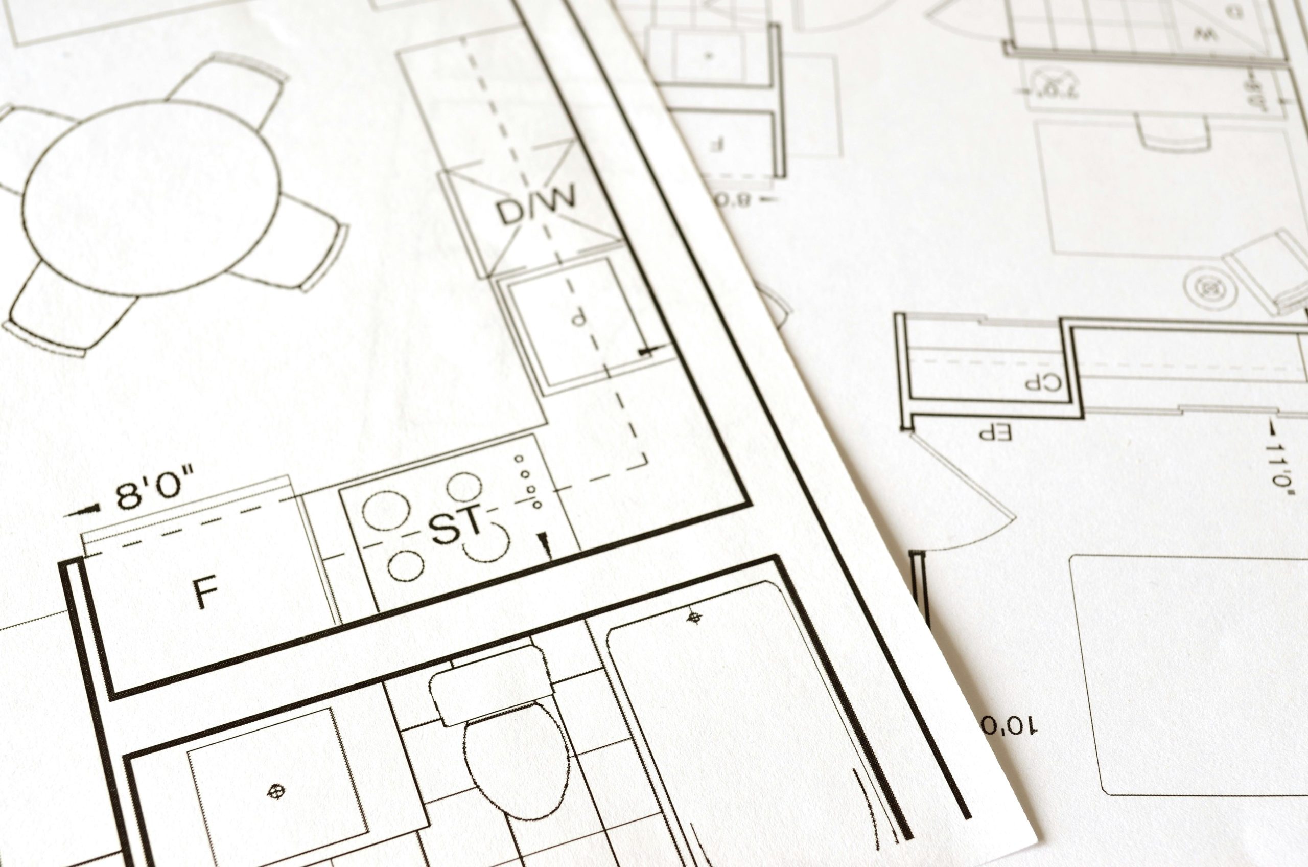 Design, Engineering & Project Management Close-up view of an architectural floor plan on paper showcasing detailed room layouts and measurements.