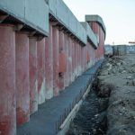 View of a construction site featuring large concrete columns, earthwork, and machinery.