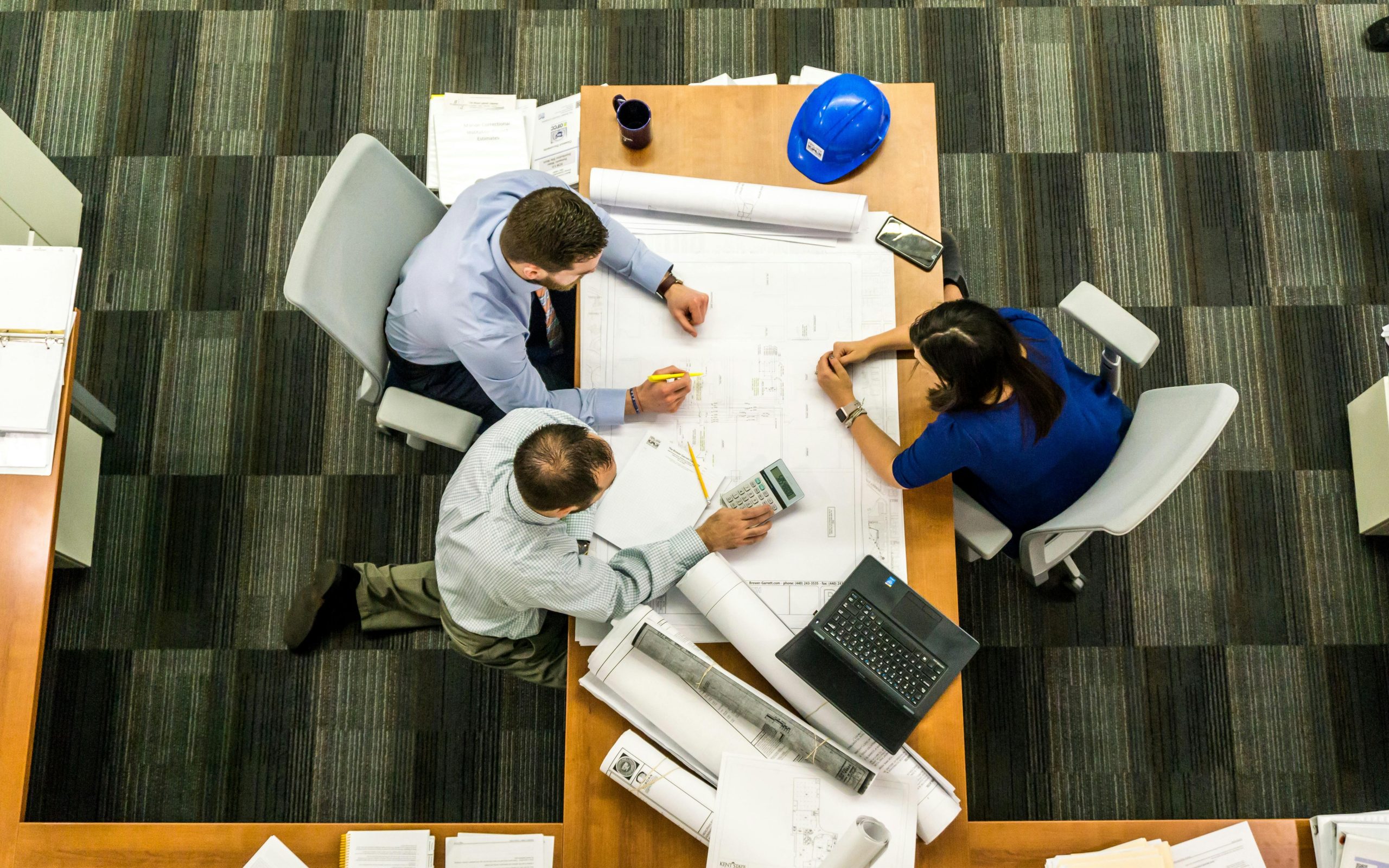 Design, Engineering & Project Management Top view of a team working on construction plans in an office setting.